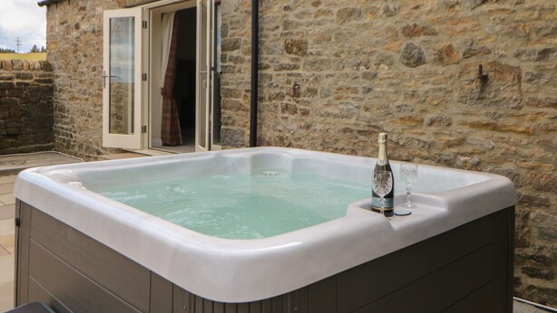 A stone building with a hot tub in the foreground. - Horsley Cottage (Consett)