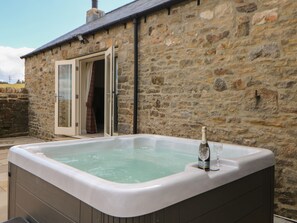 Un bâtiment en pierre avec un jacuzzi en premier plan.