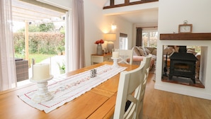 A dining area with a wooden table, chairs, a candle, and a fireplace. - The Lodge (Norwich)