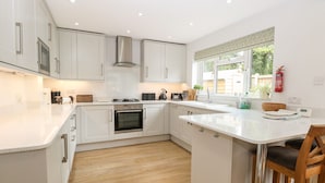 A modern kitchen with white cabinetry, a central island, and a built-in oven. - The Lodge (Norwich)