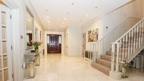 A spacious hallway with a marble floor, a grand staircase, and a large mirror. - Gleneagles (Ascot)