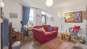 A living room with a red sofa, a wooden coffee table, a piano, and a colorful rug. - Rose Cottage (Keighley)