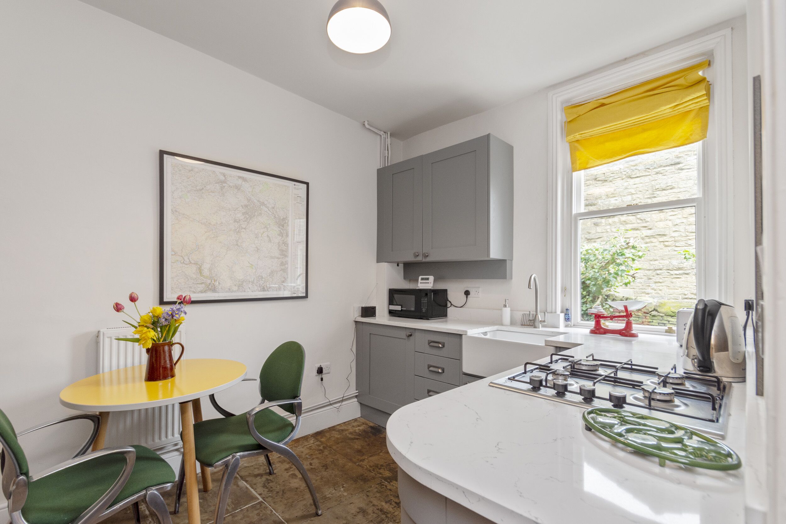 Una cocina compacta con encimera blanca, estufa y ventana con cortinas amarillas.