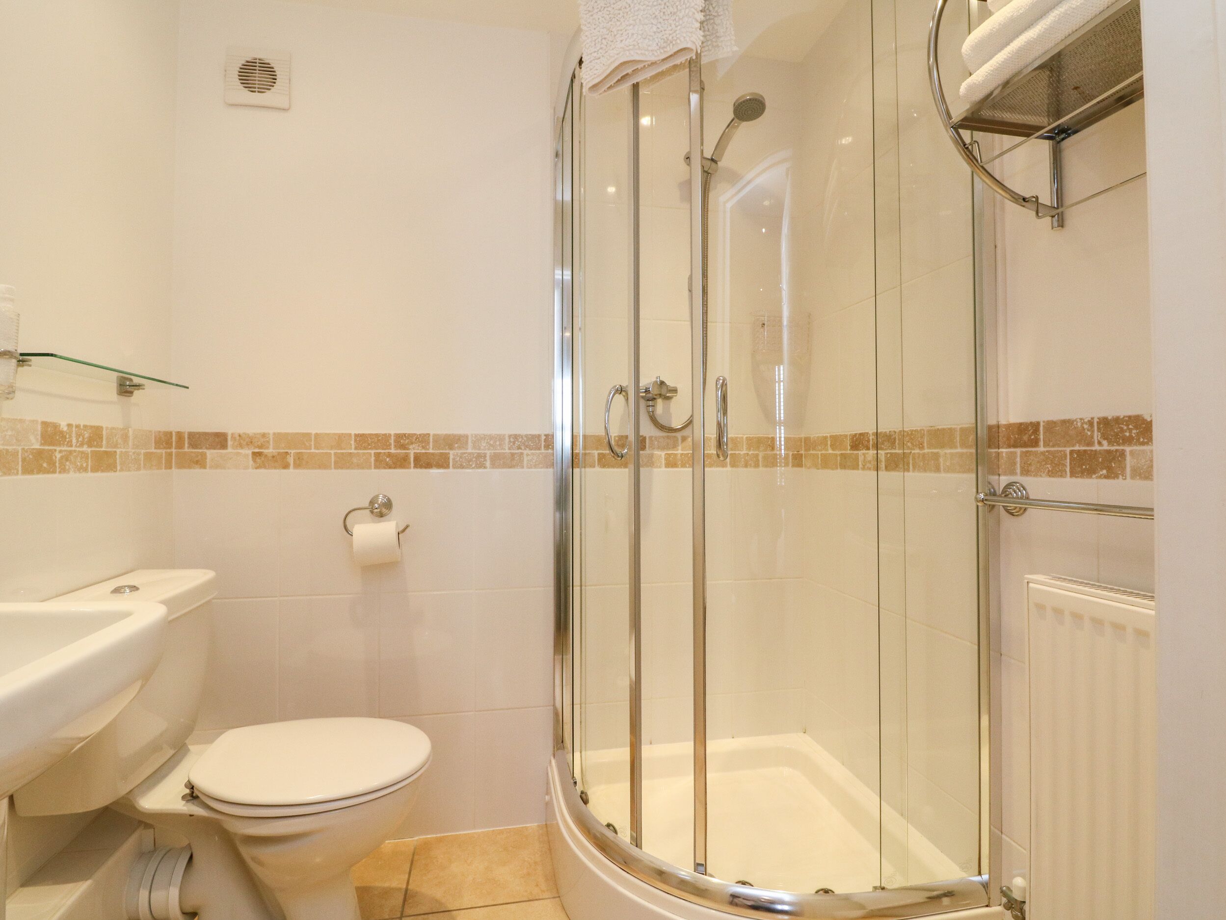 A bathroom with a glass-enclosed shower, a toilet, and a sink.