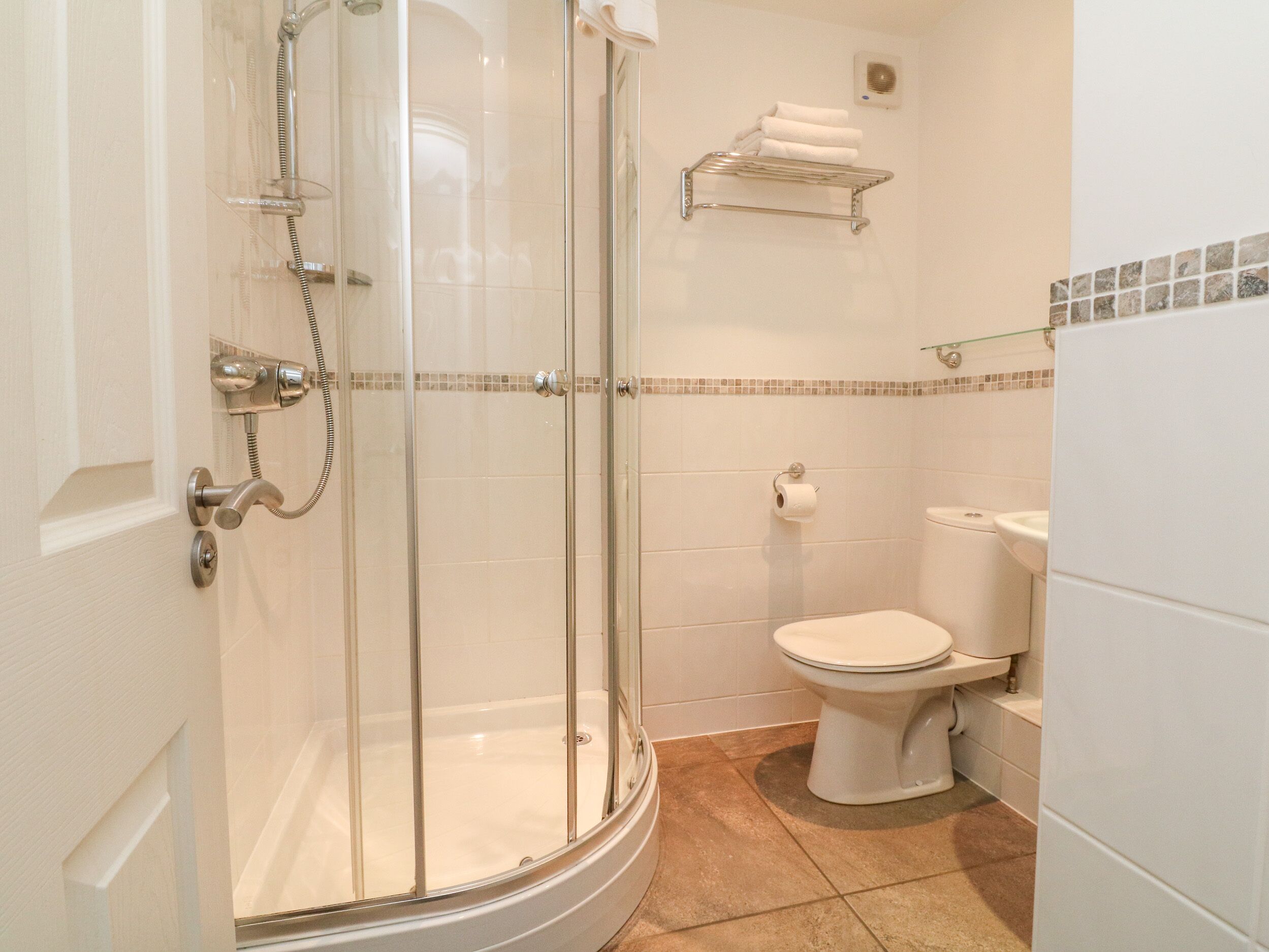 A bathroom with a glass-enclosed shower, a toilet, and a sink.