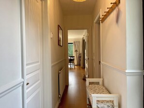 Un pasillo con un banco, un perchero y una puerta que da a otra habitación.
