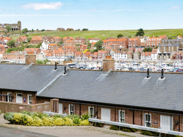 A row of brick buildings with a parking area in front. - Harbour Walk (Whitby)