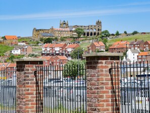 A historic building with a large arched entrance, surrounded by residential houses with red roofs.