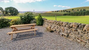 Un mur de pierres avec un banc en bois, situé dans un cadre rural.