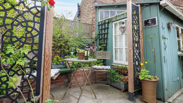 A small, enclosed garden with a table, chairs, and potted plants. - 4 Ford Street (Durham)