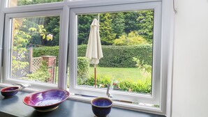 A window with a view of a garden, a white umbrella, and two bowls on the windowsill. - 4 Ford Street (Durham)