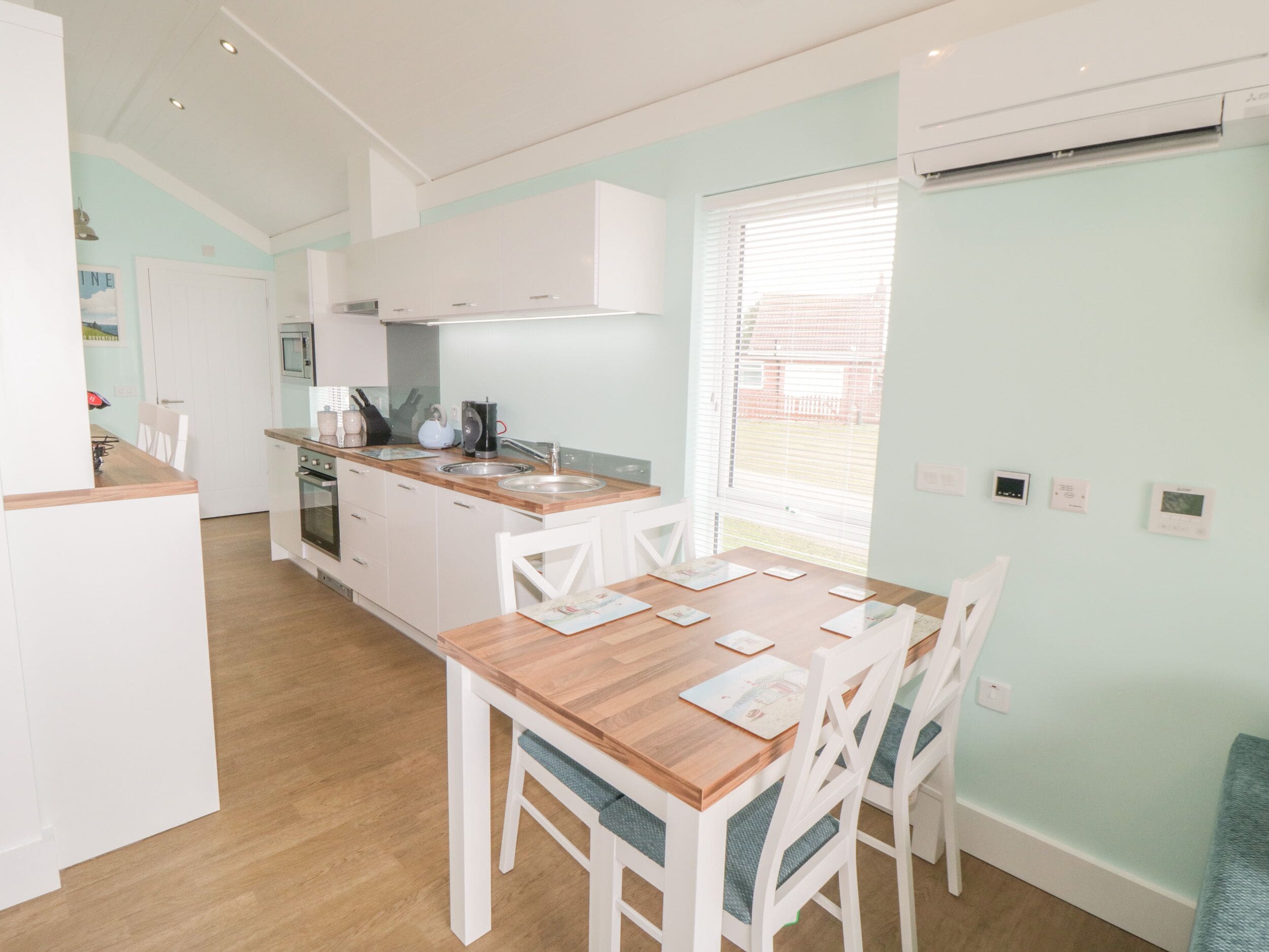 A modern kitchen with white cabinets, a wooden countertop, and a dining area with a wooden table and white chairs.