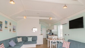 A modern living room with a sofa, a dining table, and a kitchen area. - Shore Thing 280 (Bridlington)