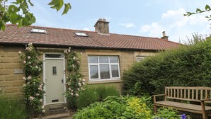 A stone cottage with a tiled roof, a white door, and a small window. - Griff Lodge (York)
