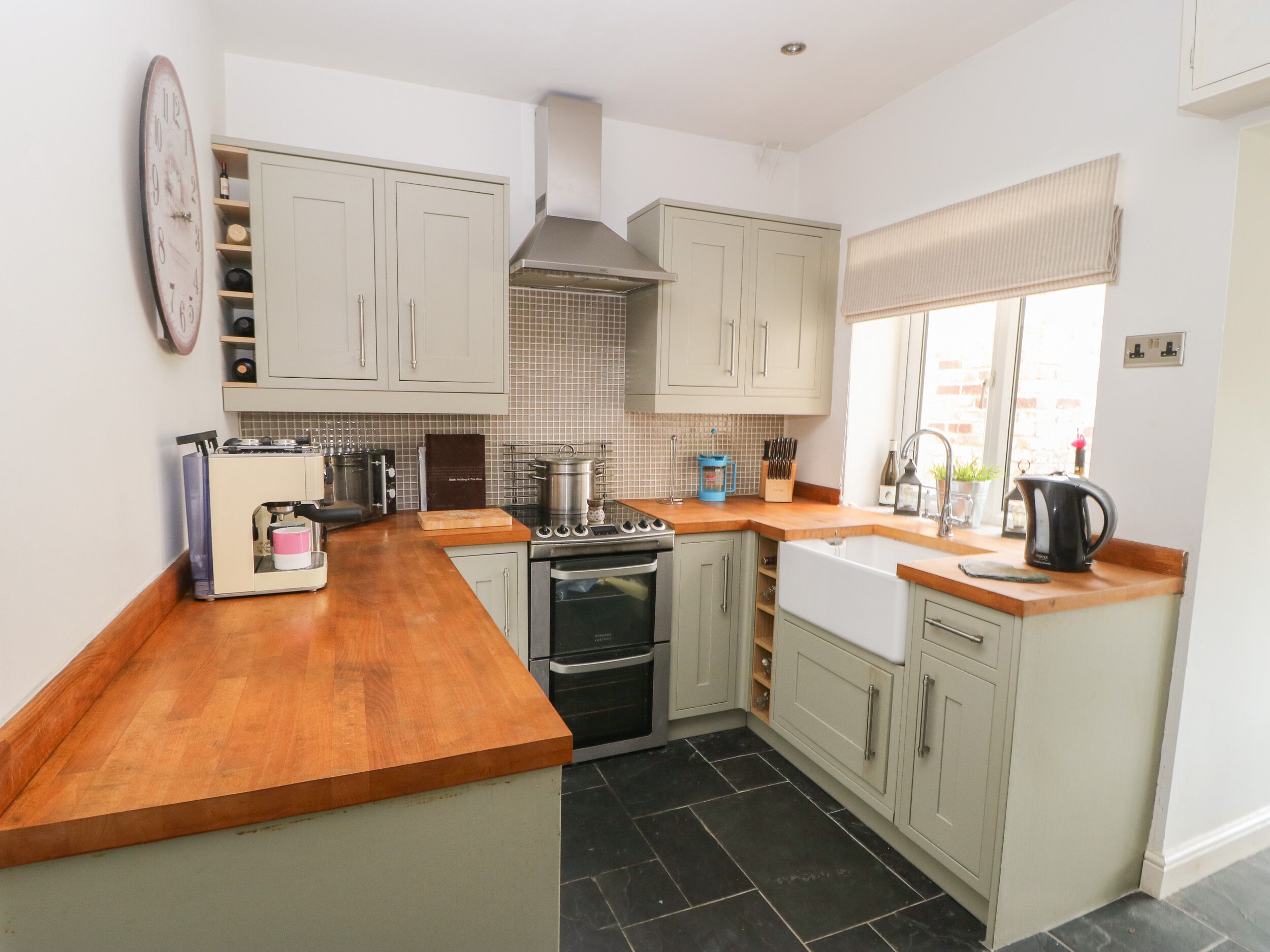 A compact kitchen with a wooden countertop, stainless steel appliances, and light-colored cabinetry.