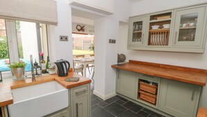 A kitchen with a wooden countertop, a sink, and cabinets. There is a window with a view of the outside. - Griff Lodge (York)