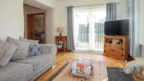 Un salon comprenant un canapé, une table basse avec des bocaux, un téléviseur et un meuble en bois.