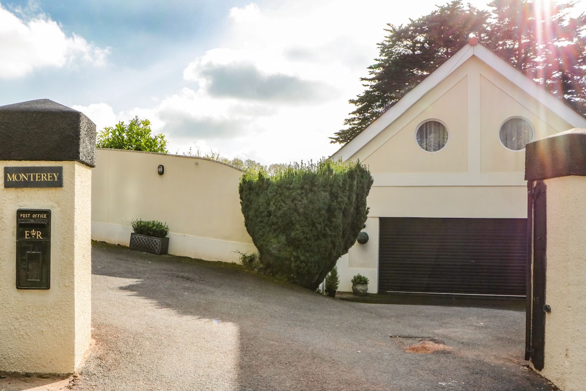 A building with a post office sign, a garage, and a hedge.