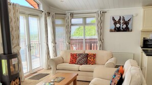 A cozy living room with a beige sofa, a wooden coffee table, and a fireplace. - Lodge 11 (Tavistock)