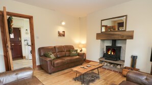 A living room with a brown leather sofa, a wooden coffee table, and a fireplace.