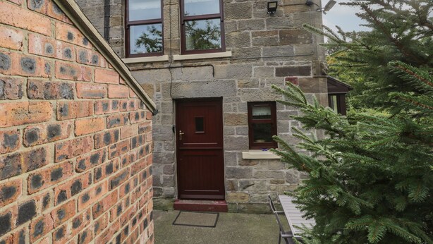A stone building with a red door and two windows.