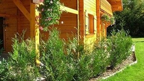 Een houten hut met een veranda, omgeven door een verzorgde tuin.