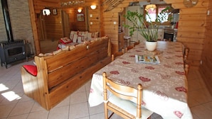 Een houten cabin met een bank, eettafel en een open haard.