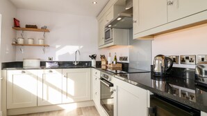 A modern kitchen with white cabinets, a black countertop, and stainless steel appliances.