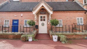 A traditional brick building with a central entrance, a blue door, and a sign reading "Derbyshire House".