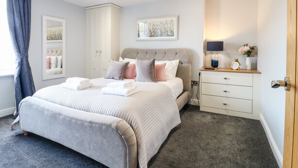 A bedroom with a bed, bedside tables, a dresser, and a mirror.