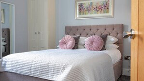A bedroom with a large bed, a wardrobe, and a painting on the wall. - Milldale (Ashbourne)