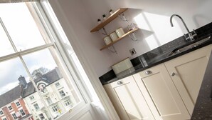 A kitchen with a window, wooden shelves, and a sink. - Milldale (Ashbourne)