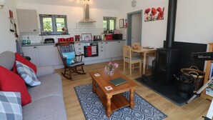 A cozy living room with a sofa, a wooden coffee table, and a fireplace. - Higher Bumsley Barn (Barnstaple)