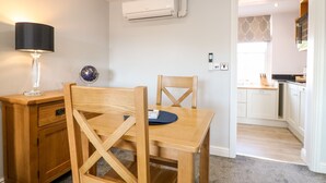 A dining area with a wooden table and chairs, a lamp, a globe, and an air conditioning unit on the wall. - Manifold Dale (Ashbourne)
