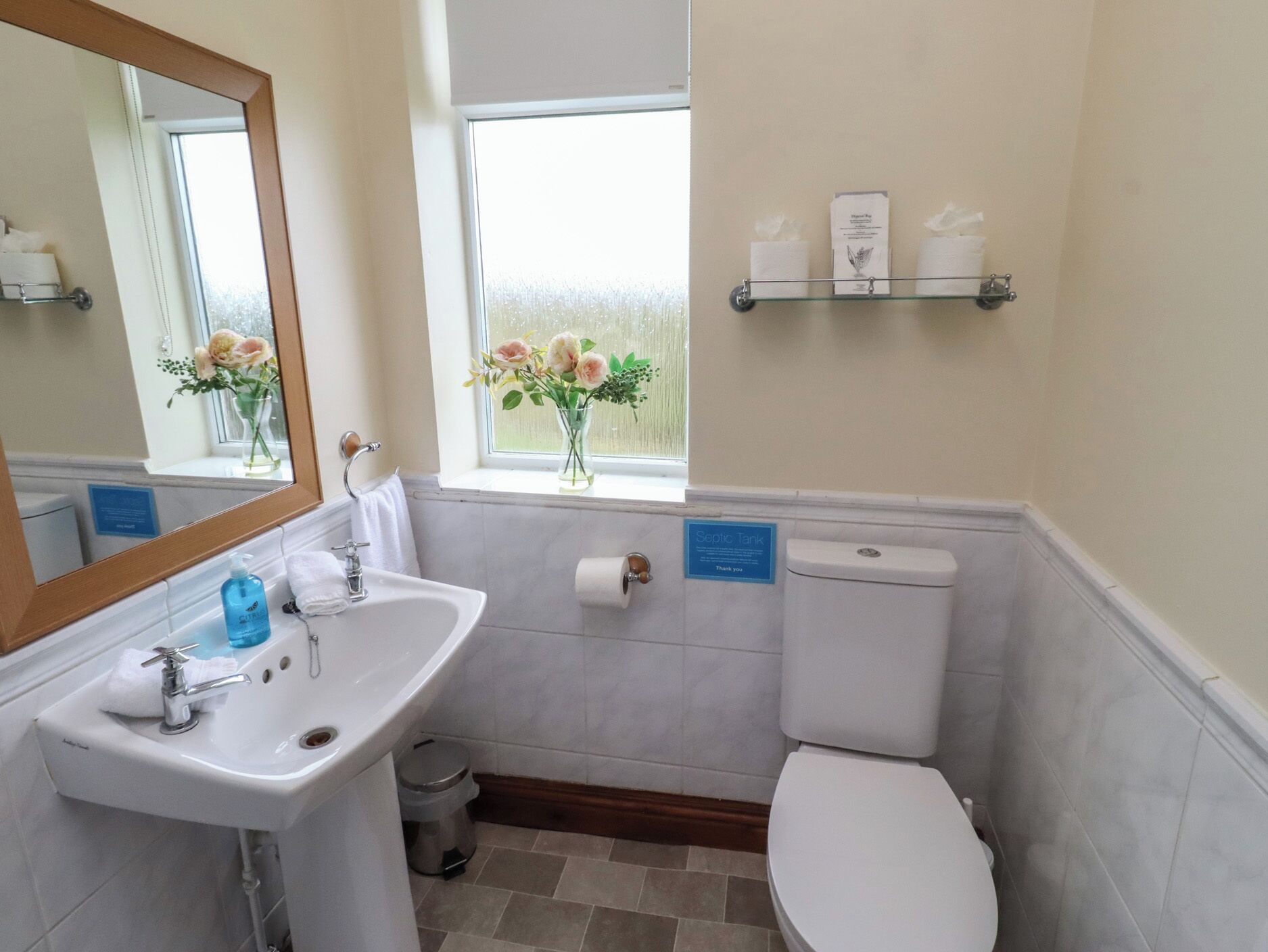 Ein Badezimmer mit Waschbecken, Spiegel, Toilette und einem Fenster mit Aussicht.
