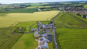Eine Luftaufnahme eines ländlichen Dorfes mit Hauptstraße, Wohnhäusern und landwirtschaftlichen Feldern.