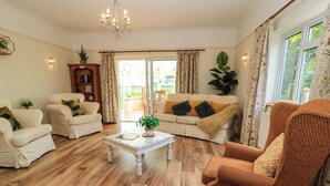 Una sala de estar con un sofá, sillones, una mesa de centro y una estantería.
