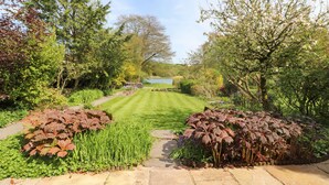 A well-maintained garden with a lawn, various shrubs, and trees. - Clerk Beck Cottage (Ulverston)