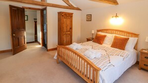 A bedroom with a wooden bed, a nightstand, a wardrobe, and exposed wooden beams. - Clerk Beck Cottage (Ulverston)