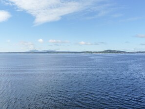 A calm sea with distant land and mountains.