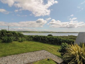 A grassy area with a gravel path leading to a body of water, surrounded by vegetation and a clear sky. - Ettrick Cottage (Rothesay)