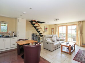 A living room with a sofa, a dining table, and a staircase. - Ettrick Cottage (Rothesay)
