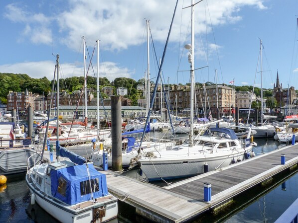 Un port de plaisance avec de nombreux bateaux amarrés, des quais en bois et des bâtiments en arrière-plan.