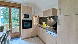 A modern kitchen with wooden cabinets, a built-in oven, a microwave, and a coffee machine. - Renovated comfortable house, great view, pets allowed (Gerbamont)