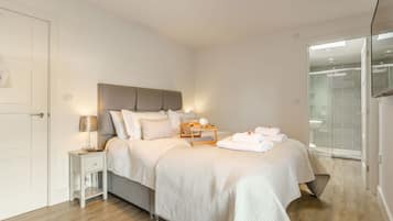 A modern bedroom with a bed, bedside table, and a glass shower area.
