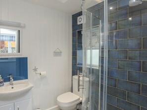 A bathroom with a white sink, toilet, and shower enclosure. - Minnehaha (Moelfre)