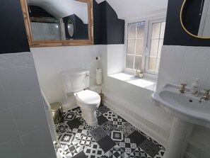 A bathroom with a toilet, sink, and window. - Farriers Cottage (Lincoln)