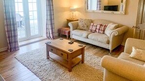 A cozy living room with a sofa, a coffee table, and a lamp. - Farriers Cottage (Lincoln)