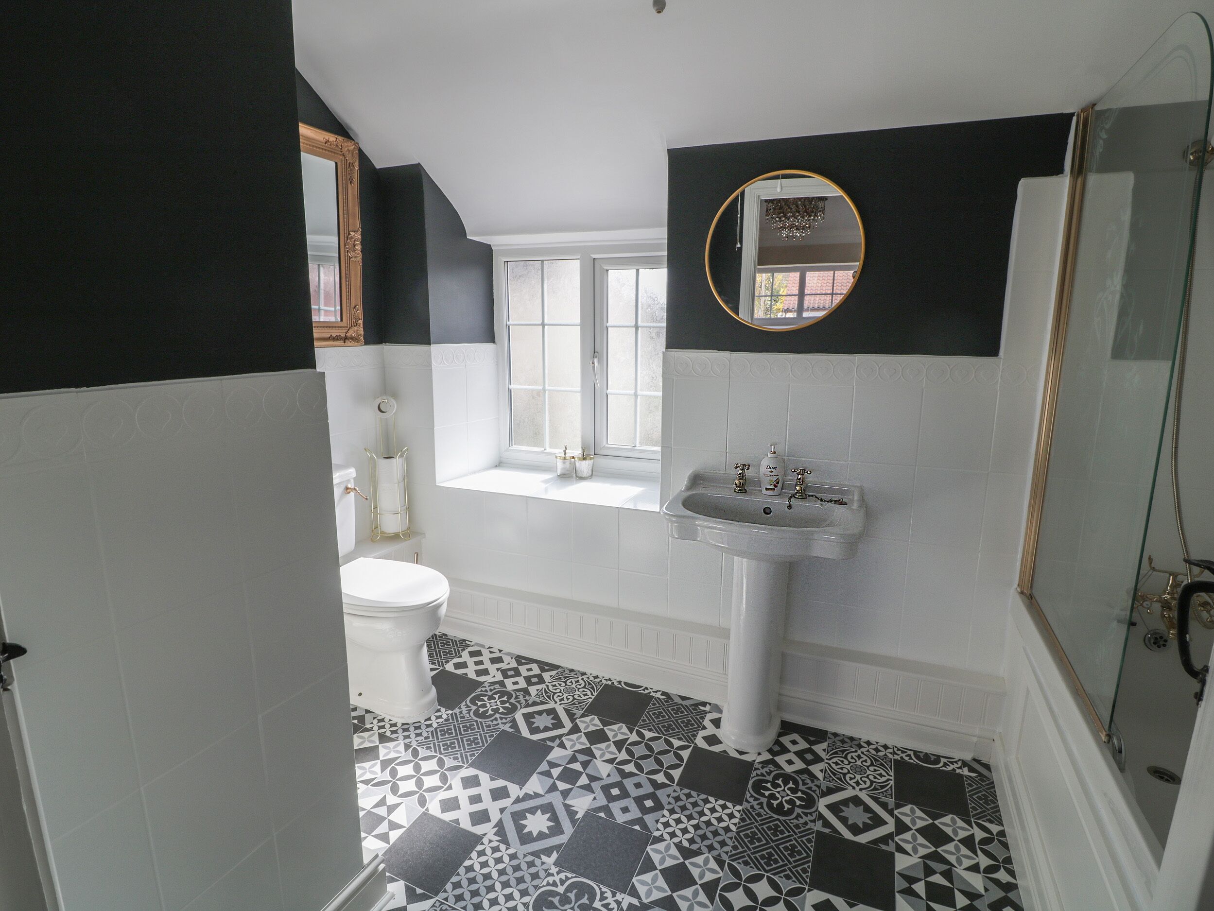 Un baño con inodoro blanco, lavamanos con espejo y bañera.