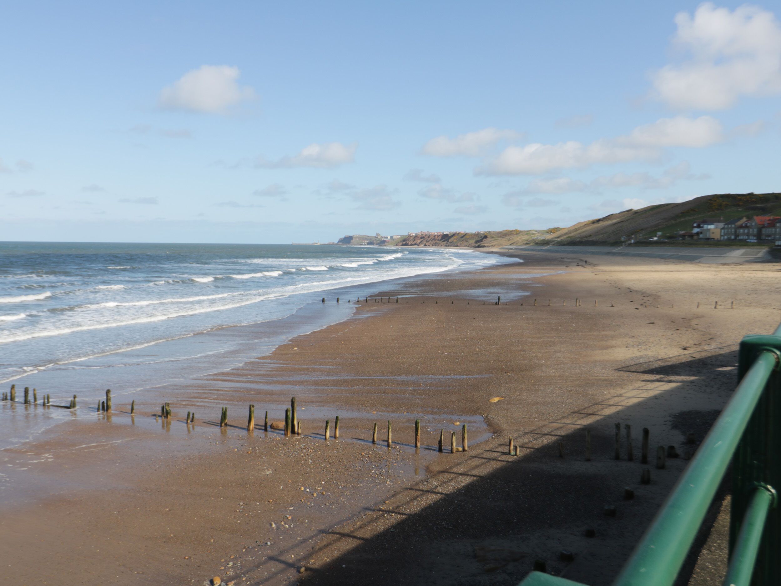 A beach with a clear view of the ocean and a distant coastline.